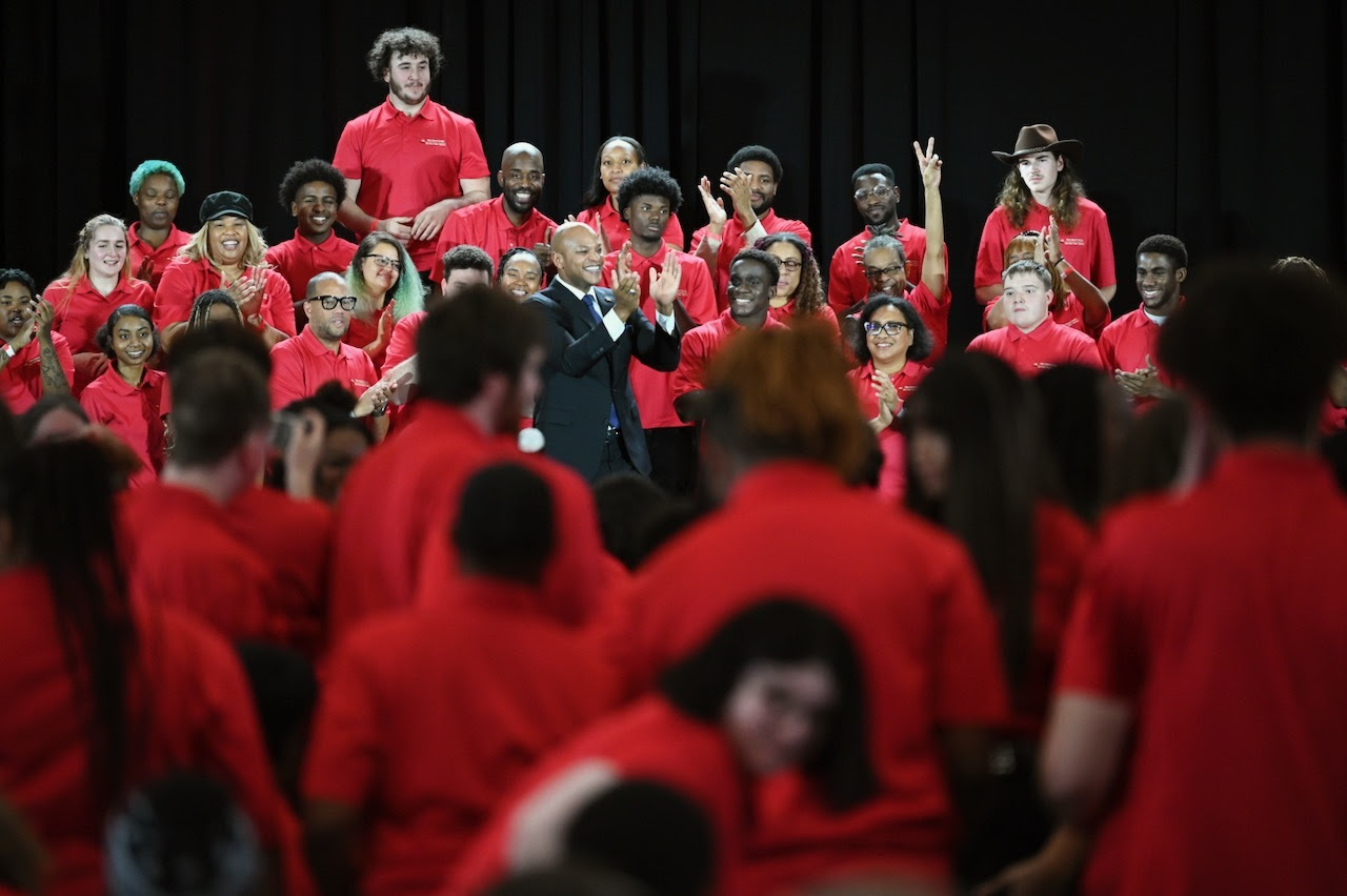 Governor Moore stands onstage with members of the Service Year Program.
